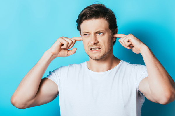 image of a homeowner covering ears due to window AC unit making noise